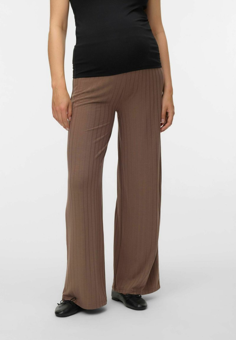 Gaišbrūna, ribota, plata kāju bikses ar mīkstu tekstūru, kurām ir brīvs piegriezums un sašaurināta potīte. Valkātas ar piegulošu melnu kreklu.