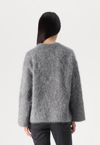 Grauer, flauschiger Pullover mit lockerer Passform, hohem Kragen und langen Ärmeln. Das strukturierte, flauschige Material sorgt für ein weiches Aussehen.