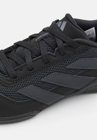 Black athletic shoe featuring a mesh upper for breathability, reinforced toe cap, and three dark stripes on the side. Laced design with padding.