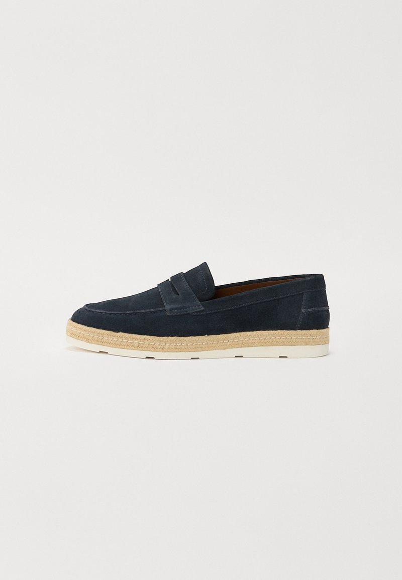 Navy suede slip-on loaferit, joissa on kevyet valkoiset kumipohjat ja punottua juuttitikkausta reunassa; sileä pinta ja yksinkertainen muotoilu.