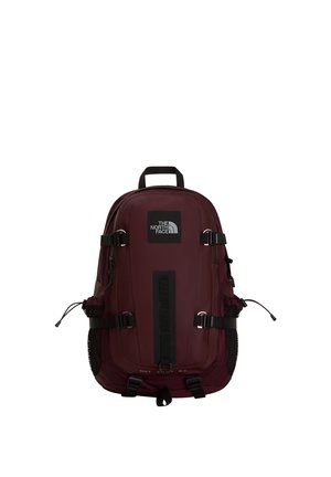 Mørkerød North Face rygsæk med flere stropper, net-lommer på siderne, topgreb og frontlogo-patch midt på en hvid baggrund.