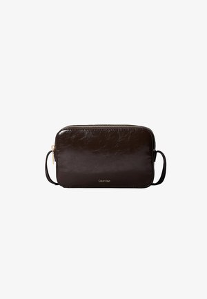 Sac bandoulière rectangulaire en cuir marron foncé avec fermeture éclair dorée et fine bandoulière, petit logo Calvin Klein centré sur le devant.