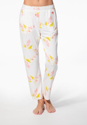 Weiße elastische Taillenhose mit rosa Traubenbüscheln und gelben Blättern, getragen von einer stehenden Person, barfuß auf weißem Hintergrund.