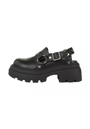 Schwarzer klobiger Plateauschuh mit offenem Fersenbereich, verstellbarem Schnallenriemen und dicker profillierter Sohle.