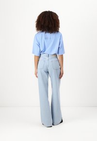 Ljust blå oversized t-shirt med korta ärmar och rund halsringning, i kombination med högmidjade ljusblå vida jeans med bakfickor.
