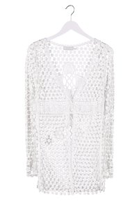 Vit virkad cardigan med V-ringning, långa ärmar och detaljerade blommönster. Lätt, genomskinlig struktur med öppen frontdesign.