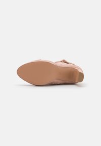 Scarpa in suede rosa con finitura liscia, punta affusolata e tacco basso; presenta una piccola fibbia decorativa e un dettaglio di cucitura.