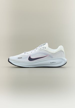 Zapatilla de correr blanca de Nike con el logo swoosh en negro y rosa, parte superior de malla y suela gruesa acolchada etiquetada como "ComfiRide" sobre fondo neutro.