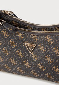 Svart teksturert fuskeskinnspose med glidelås, med et mønster av et sammenflettet gull-logo og en gull trekantet logo-plate. To glidelåslukkinger.