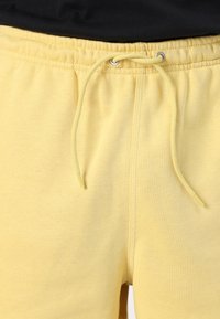 Κίτρινες βαμβακερές φόρμες με ελαστική μέση, ρυθμιζόμενο κορδόνι και λεία υφή. Έχουν μινιμαλιστικό σχέδιο χωρίς μοτίβα.