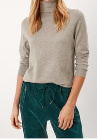 Pull à col roulé en maille gris clair à manches longues, associé à un pantalon en velours côtelé bleu sarcelle avec une taille à cordon de serrage et des poches latérales.