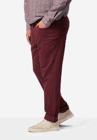 Pantalones burdeos de corte recto, con bolsillos laterales y costuras visibles; combinados con zapatillas de tono claro. Tejido suave, diseño casual.