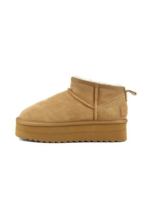 Tan suede ankle boot with thick brown rubber sole, visible stitching, and a pull tab on the heel, lined with white soft material.