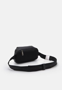 Svart tvärs över kroppen väska gjord av texturerat tyg med en slät ovansida, dragkedjestängning och justerbar rem med upprepande varumärke.