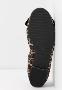 Płaskie buty w panterkę z teksturowaną cholewką z materiału, czarną gumową podeszwą i minimalnym wzorem bieżnika dla lepszej przyczepności.