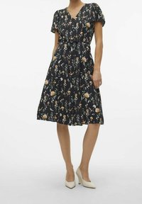 Robe fleurie avec un fond noir, manches courtes bouffantes, col en V, ceinture à la taille, jupe évasée et poches latérales. Ornée de fleurs de différentes couleurs.