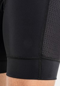 Pantalones cortos deportivos negros con un panel de malla texturizada, tejido suave y costuras reforzadas. Ajustados cerca del muslo con una cinturilla elástica.