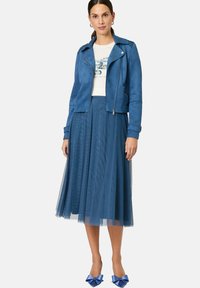 Blue faux suede cropped jacket, white graphic t-shirt, layered blue tulle skirt, and blue bow-detail heels.