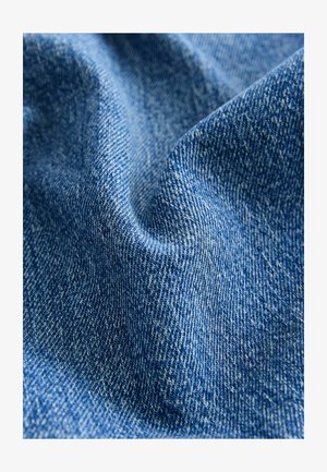 Tessuto di denim in blu profondo, con una consistenza morbida e una leggera lucentezza, caratterizzato da un motivo di tessitura diagonale e sottili variazioni di colore.
