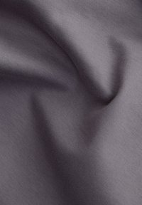 Grauer Stoff mit glatter Textur, der subtile Falten und Wendungen aufweist, die seine leichte und fließende Qualität zur Schau stellen.