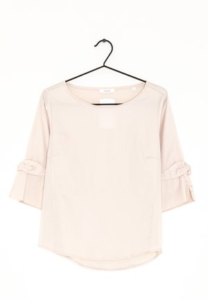 Camicia rosa chiaro con maniche a tre quarti, con dettagli arricciati e laccetti alle estremità delle maniche, scollo rotondo e orlo curvo.