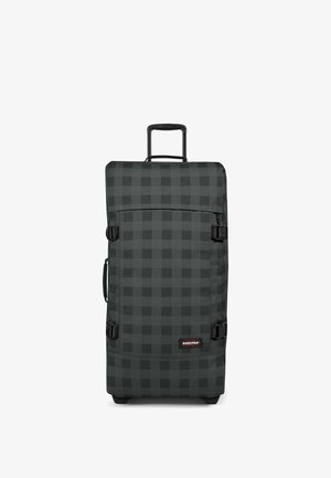 Maleta alta de ruedas con estampado de cuadros negros y grises, asa extensible, asa lateral, correas de compresión y logo de Eastpak en la esquina inferior frontal.