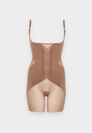 Μπεζ ολόσωμο σχήμα χωρίς ραφές με ρυθμιζόμενους ιμάντες ώμων που φτάνουν στο μέσο μηρού σε ουδέτερο φόντο.