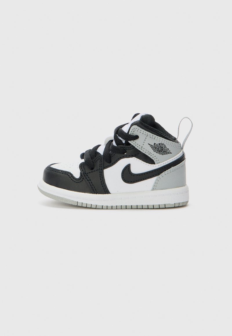 Baskets pour tout-petit en noir, blanc et gris avec une tige en cuir et synthétique, un embout texturé, des lacets noirs et un logo signature sur le côté.