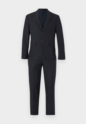 Tumehall meeste kahe nupuga ülikonnajakk sobivate pükstega, sälkraua, klapiga taskute ja kitsase lõikega valgel taustal.