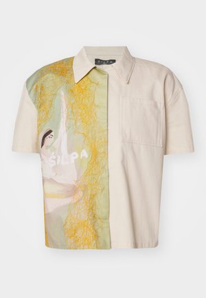 Trumpas rankovės marškinis, pasižymintis kreminės spalvos audiniu su spalvingu, meniniu dizainu žaliais ir geltonais atspalviais vienoje pusėje, ir kišenė.