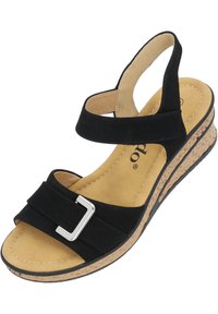 Sandalía negra con tacón de corcho, que presenta un diseño de correa suave, acento de hebilla plateada y plantilla acolchada beige.