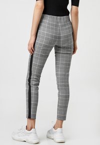 Gray plaid trousers with a slim fit, featuring a black side stripe. Made from fabric with a smooth texture, designed for a contemporary look.
