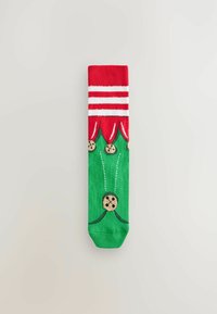 Chaussettes vertes avec un haut rouge orné de rayures blanches, décorées de motifs de biscuits et d'accents verts, fabriquées en tissu doux.