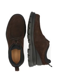 Scarpe in suede marrone con una robusta suola in gomma nera, caratterizzate da un design con lacci e un vano posteriore per facilitarne l'indossamento.