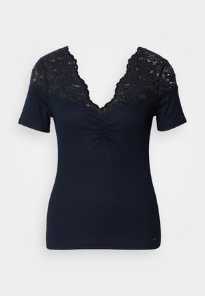 Marineblauwe top met korte mouwen en een diepe V-hals, met een kant yoke en geplooide details bij de buste. Ribbelstructuur over de hele top.