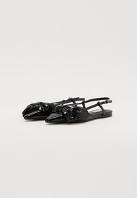 Black patent leather slingback flats with pointed toes, featuring a knotted bow detail on the front and thin strap closure.