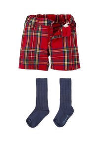 Pantalones cortos a cuadros rojos con cierre de botón y cintura elástica, combinados con calcetines de canalé navy hasta la rodilla. Los pantalones cortos tienen detalles en verde y amarillo.