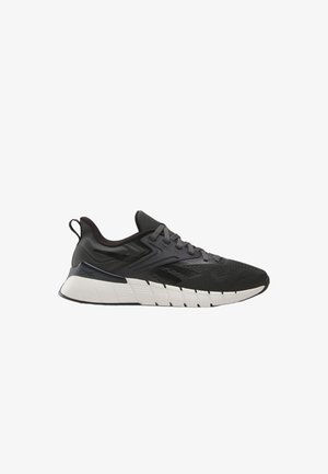 Scarpa sportiva nera e grigia con suola segmentata bianca, tomaia in mesh, chiusura con lacci e linguetta sul tallone, vista laterale su sfondo bianco.