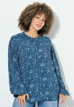 Blå bluse med blomsterprint, lange ærmer, knaplukninger og en samlet halsudskæring. Lavet af et blødt stof med en afslappet pasform.