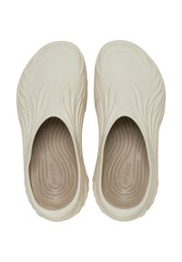Beżowe Crocs z falistą fakturą na górze, łatwe do zakupu, z wyściełanym wnętrzem. Lekkie materiały z subtelnym logo na wkładce.
