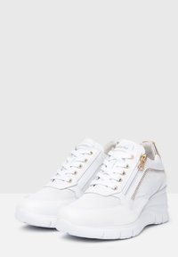 White sneakers with a textured upper, gold accents, a side zipper, and sturdy rubber soles. Features a lace-up design with metal eyelets.