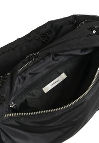 Fekete szövet kézitáska cipzárral, fekete flitterekkel díszítve, belső címkével, amelyen az "InWear" felirat áll.