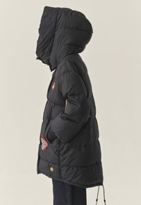 Juodasis pūkuotas džemperis su kapišonu, su pagalvėlėmis ir siuvinėjimu priekyje, taip pat šoniniais kišenėmis. Lygus tekstūros ir prigludęs siluetas.