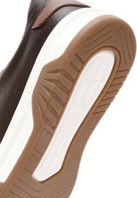 Zapatilla sintética marrón con parte superior texturizada, media suela blanca y suela de goma con un patrón de tracción para agarre. Con acentos en cuero marrón.