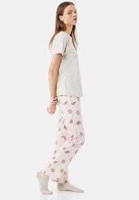 Lys grå kortærmet T-shirt med en afslappet pasform, parret med lyserøde pyjamasbukser med et trykt mønster af croissanter og svulmønstre.