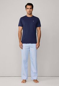 Navyblauw T-shirt met korte mouwen, gecombineerd met lichtblauwe, losvallende broek; beide gemaakt van zachte stof, zonder zichtbare logo's of patronen.