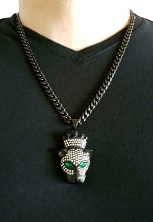 Collana con catena nera che presenta un ciondolo a forma di testa di pantera dettagliata, abbellita da occhi di pietra verde e una corona, con una texture di strass.