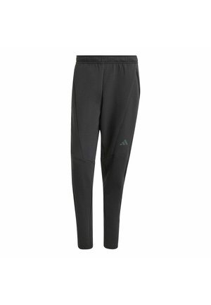 Pantalons de sport noirs ajustés, fabriqués à partir d'un matériau doux. Comprend des poches latérales et un accent en logo sur la cuisse gauche.