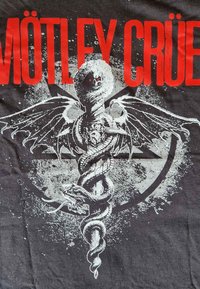 Černé grafické tričko s bílou ilustrací okřídlené postavy se hady a tučným červeným textem "MÖTLEY CRÜE."