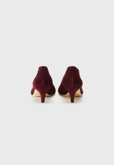 Scarpe in suede borgogna con tacco basso, caratterizzate da dettagli perforati e un interno liscio. La forma è elegante con una punta rotonda.